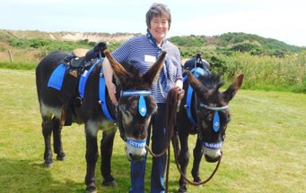 Volunteer holding donkeys outside the Sand Bothy at the RNLI fun day event