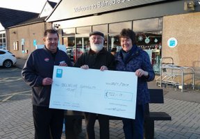 Three people holding giant cheque outside Balmedie Co-op store